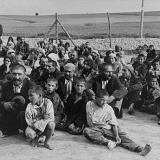 Un gruppo di prigionieri rom in attesa di istruzioni dai loro carcerieri tedeschi, seduti in un'area parta vicino la recinzione, campo di concentramento di Belzec, 1940, United States Holocaust Memorial Museum courtesy of Archiwum Dokumentacji Mechanicznej.